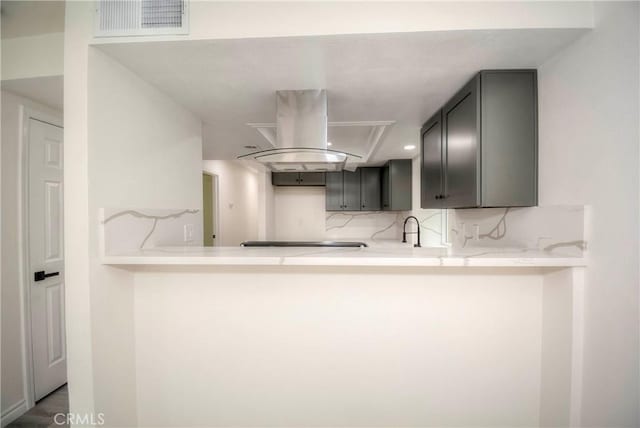 kitchen with sink, stovetop, tasteful backsplash, island range hood, and kitchen peninsula