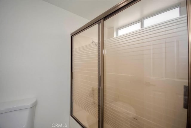 bathroom with toilet and a shower with shower door