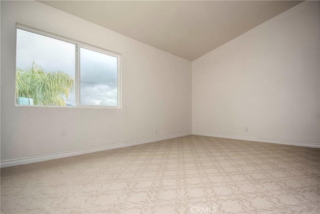 carpeted spare room with vaulted ceiling