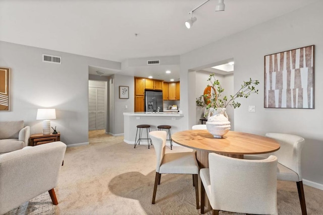 dining space featuring light carpet and rail lighting