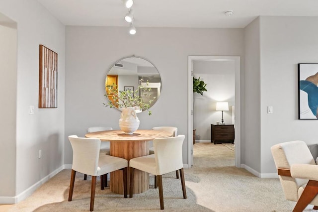 carpeted dining room with track lighting