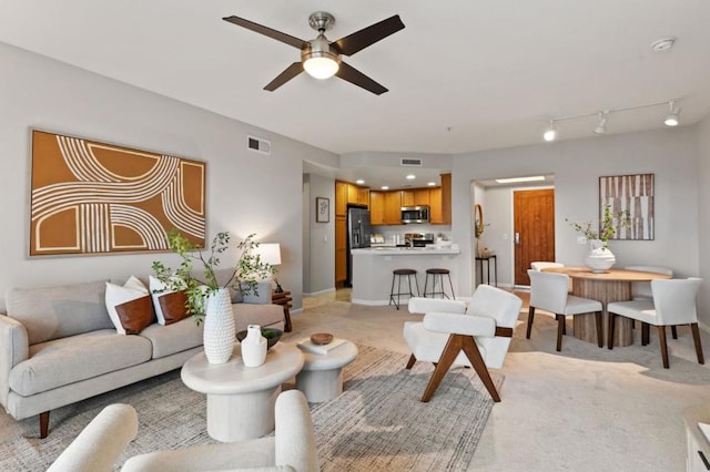 living room with ceiling fan, light colored carpet, and rail lighting