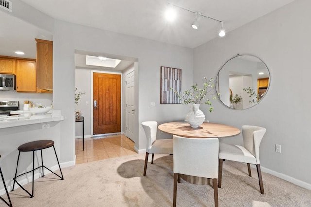 dining area featuring rail lighting, light carpet, and a skylight