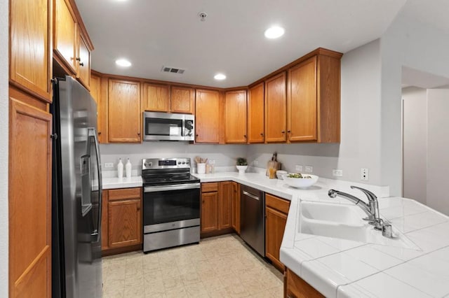 kitchen with stainless steel appliances, tile counters, and sink