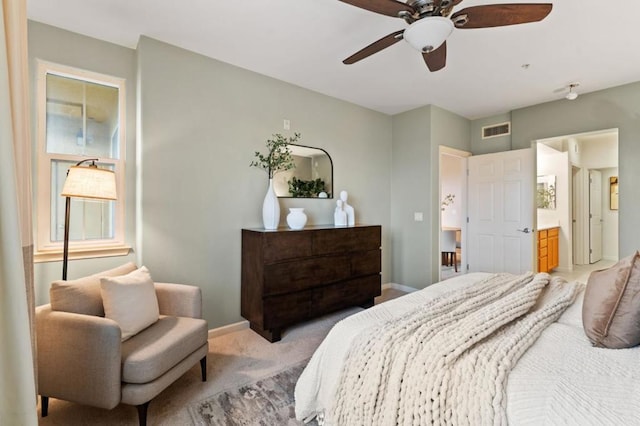 bedroom featuring ensuite bathroom, light colored carpet, and ceiling fan