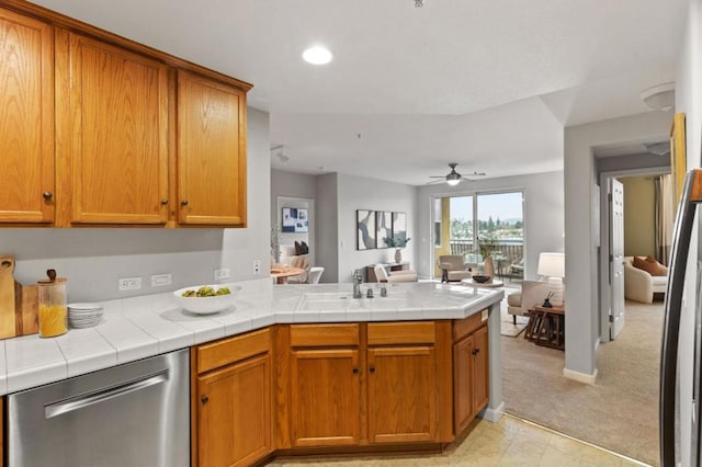 kitchen featuring sink, tile countertops, dishwasher, kitchen peninsula, and ceiling fan