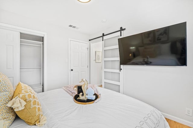 bedroom featuring hardwood / wood-style flooring, a barn door, and a closet