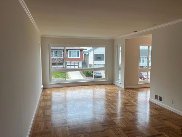 unfurnished room featuring parquet flooring, ornamental molding, and a healthy amount of sunlight