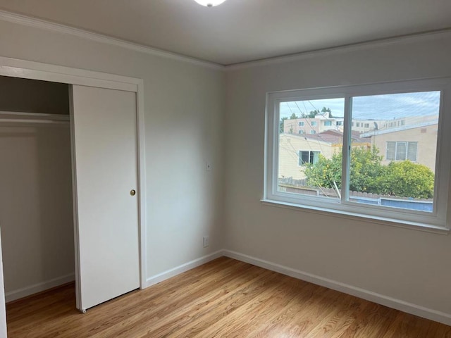 unfurnished bedroom with ornamental molding, light hardwood / wood-style floors, and a closet