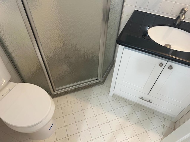 bathroom with backsplash, vanity, toilet, a shower with door, and tile patterned floors