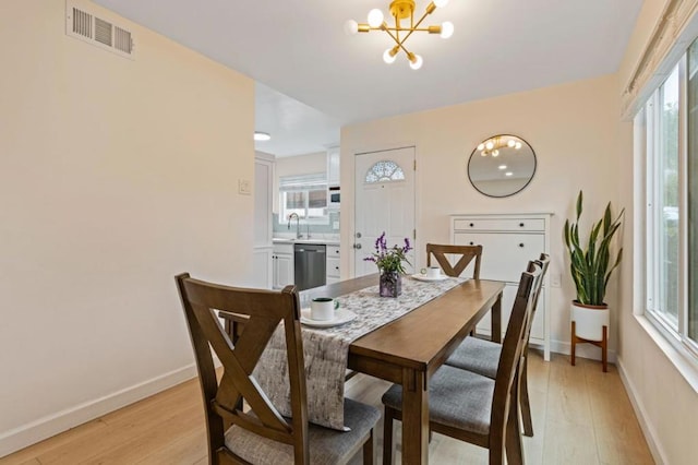 dining room featuring a chandelier, sink, and light hardwood / wood-style flooring