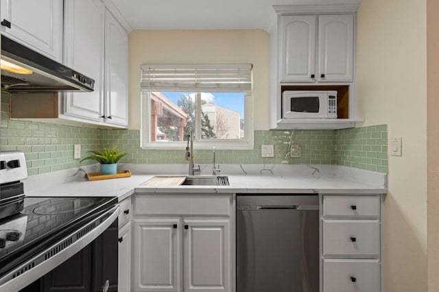 kitchen with sink, appliances with stainless steel finishes, white cabinetry, backsplash, and light stone counters