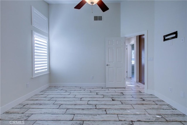 unfurnished room with ceiling fan, light hardwood / wood-style floors, and a towering ceiling