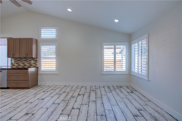 interior space featuring tasteful backsplash, lofted ceiling, dishwasher, and light hardwood / wood-style flooring