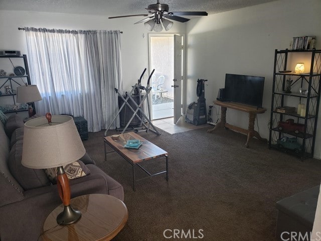 living room featuring ceiling fan, a textured ceiling, and carpet