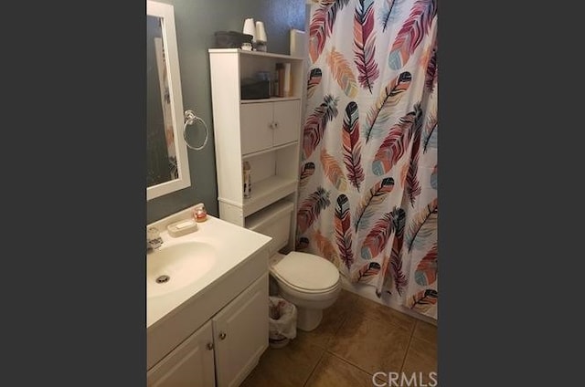 bathroom with tile patterned flooring, vanity, toilet, and walk in shower