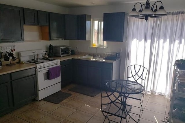 kitchen featuring light tile patterned flooring, an inviting chandelier, sink, and white gas stove