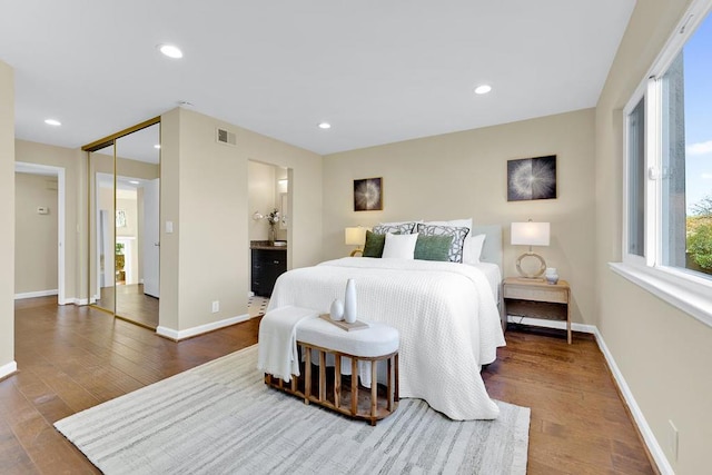 bedroom featuring ensuite bath, dark wood-type flooring, and a closet