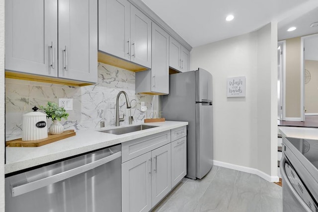 kitchen featuring stainless steel appliances, sink, gray cabinets, and decorative backsplash