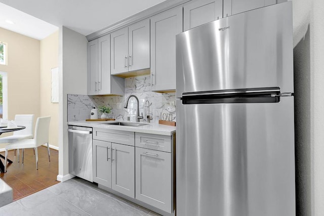 kitchen featuring tasteful backsplash, appliances with stainless steel finishes, sink, and gray cabinetry