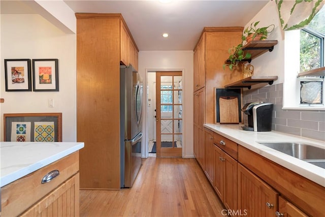 kitchen featuring stainless steel refrigerator, decorative backsplash, light hardwood / wood-style flooring, and a wealth of natural light