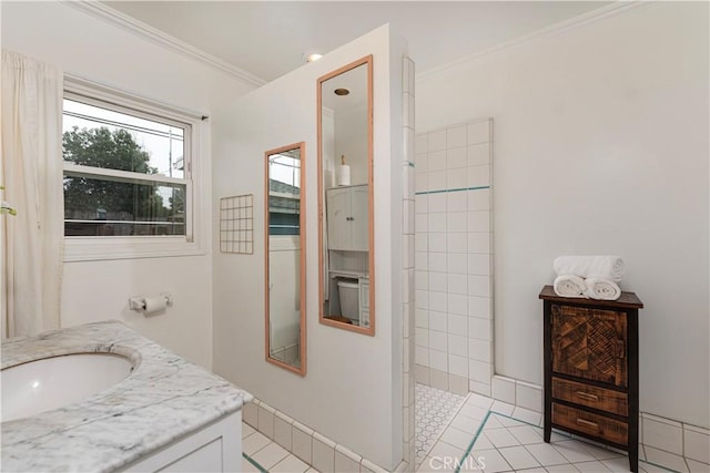 bathroom featuring tile patterned flooring, vanity, a tile shower, and crown molding