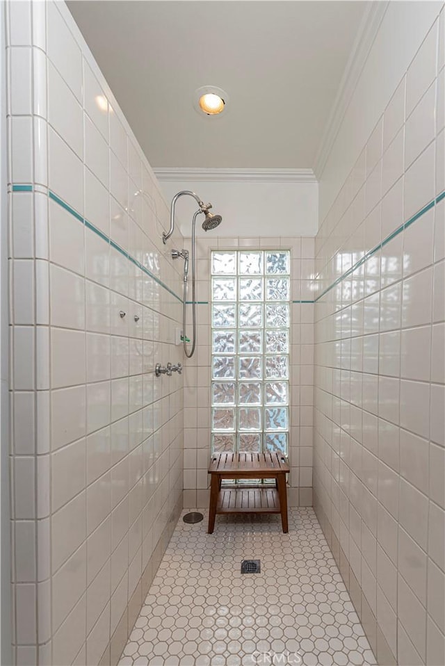 bathroom with ornamental molding and a tile shower