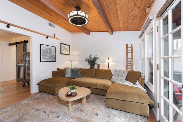 living room featuring beamed ceiling, a barn door, wood ceiling, and light hardwood / wood-style flooring