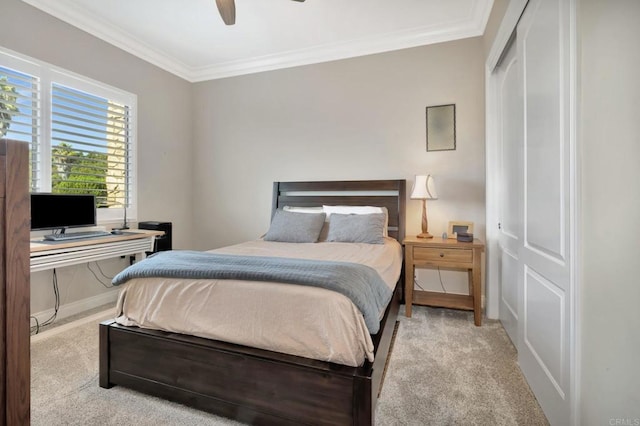 bedroom with ceiling fan, ornamental molding, a closet, and light colored carpet