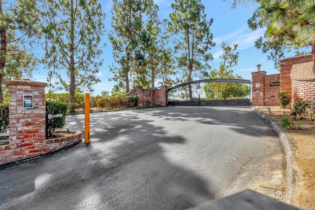 view of street featuring a gate, a gated entry, and curbs