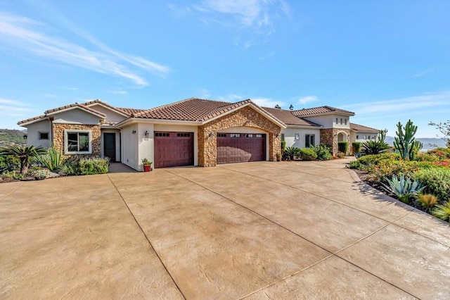 view of front of home featuring an attached garage, stone siding, concrete driveway, a tiled roof, and stucco siding