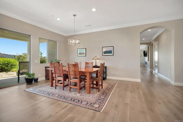 dining space featuring arched walkways, crown molding, recessed lighting, light wood-style floors, and baseboards