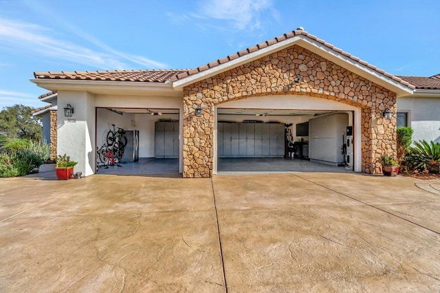 exterior space with concrete driveway, stone siding, a tiled roof, an attached garage, and stucco siding