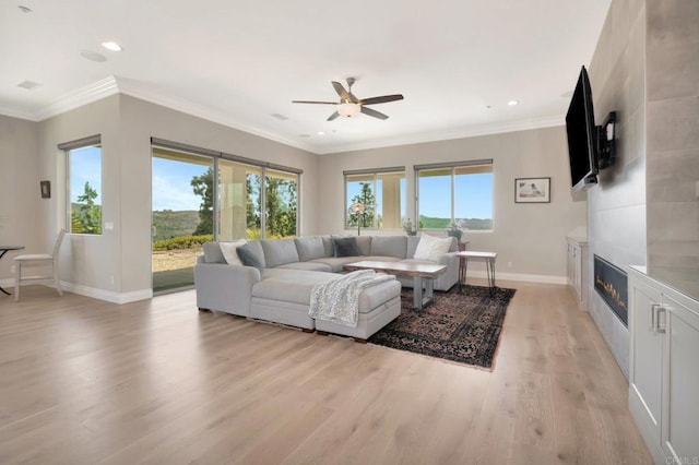 living room featuring a large fireplace, light wood finished floors, crown molding, and baseboards