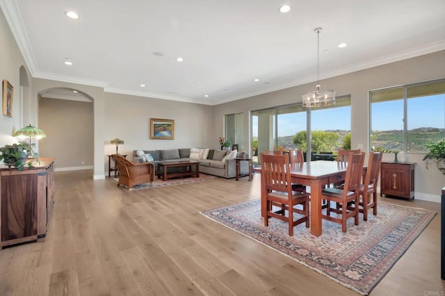 dining space with light wood-style floors, ornamental molding, baseboards, and an inviting chandelier