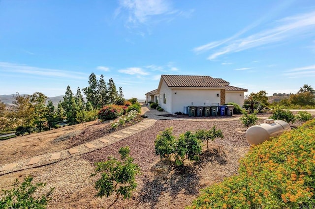 back of house featuring a tiled roof and stucco siding