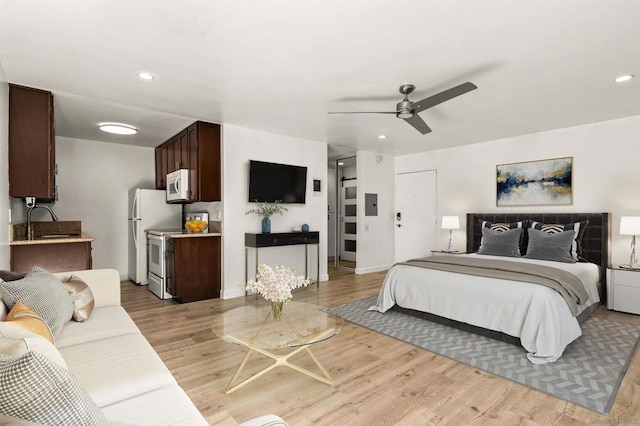 bedroom with sink, light hardwood / wood-style flooring, and ceiling fan