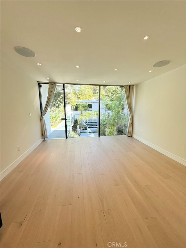 unfurnished room featuring a wall of windows and light hardwood / wood-style flooring