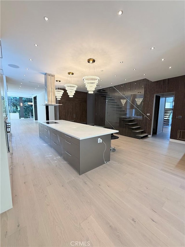 kitchen featuring an inviting chandelier, decorative light fixtures, a spacious island, and light wood-type flooring