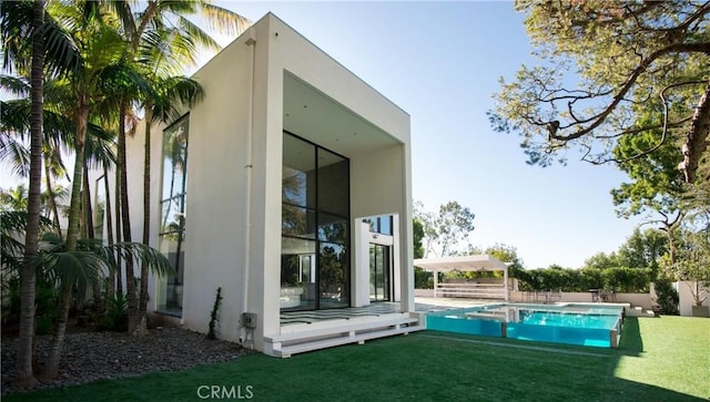 rear view of house featuring a fenced in pool and a yard