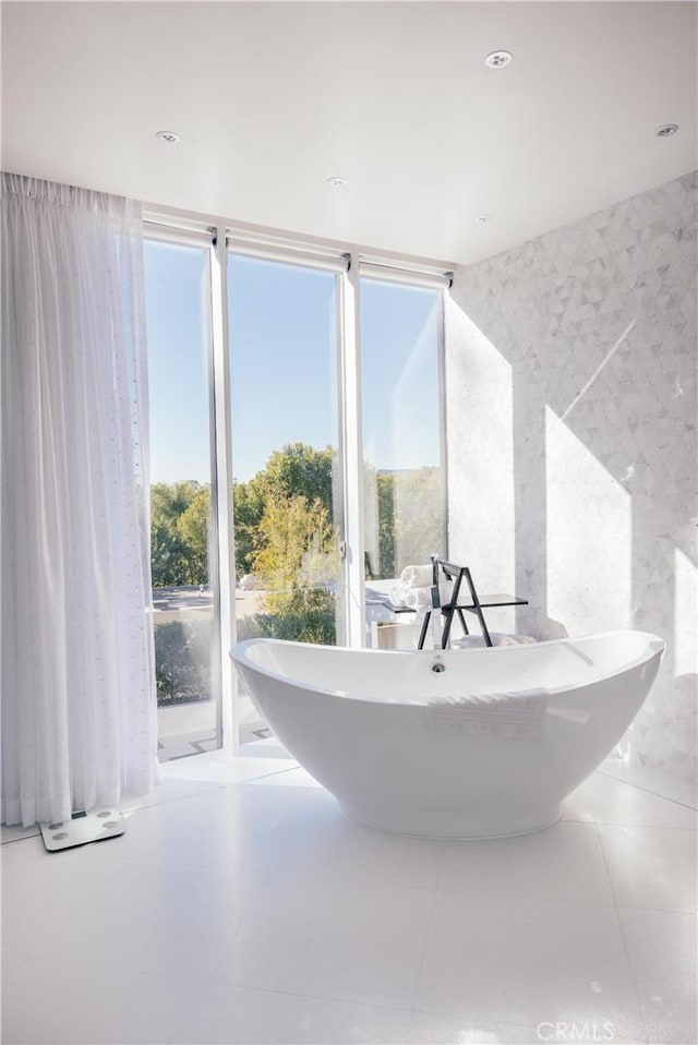 interior space with expansive windows, tile patterned floors, plenty of natural light, and a bath