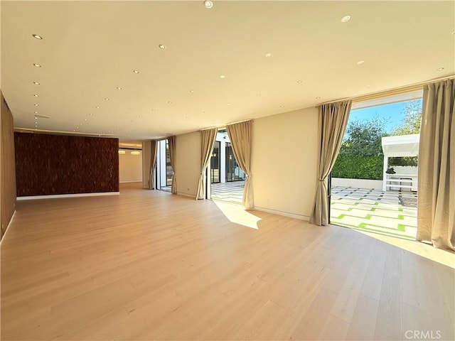 unfurnished room featuring expansive windows and light hardwood / wood-style flooring