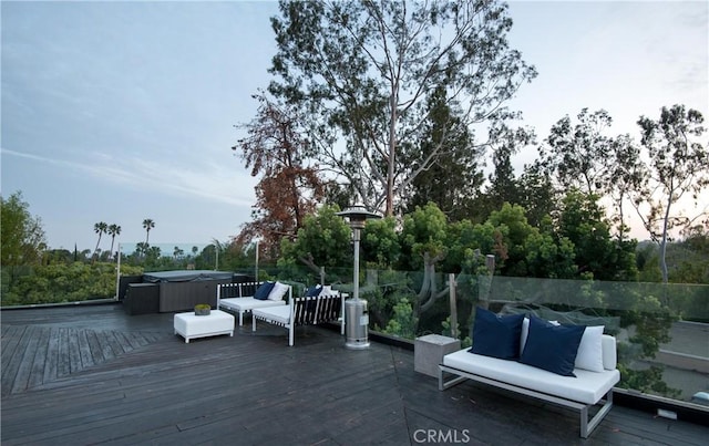 deck at dusk with a hot tub and outdoor lounge area