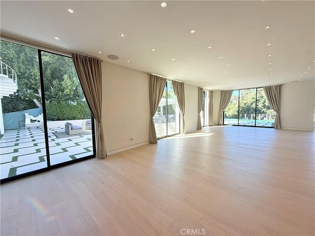 unfurnished room featuring floor to ceiling windows, plenty of natural light, and light wood-type flooring