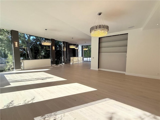 empty room featuring floor to ceiling windows, hardwood / wood-style floors, and an inviting chandelier