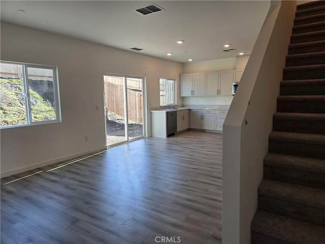 interior space featuring a wealth of natural light, dishwasher, hardwood / wood-style floors, and white cabinets