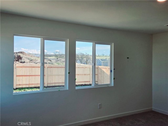 empty room with dark colored carpet and a mountain view