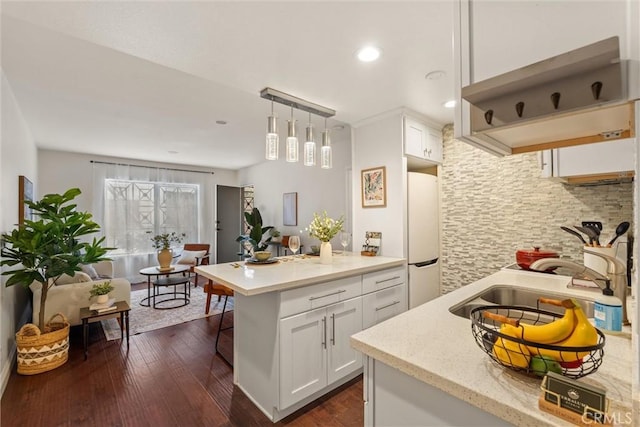 kitchen featuring pendant lighting, sink, white cabinets, a kitchen bar, and white fridge