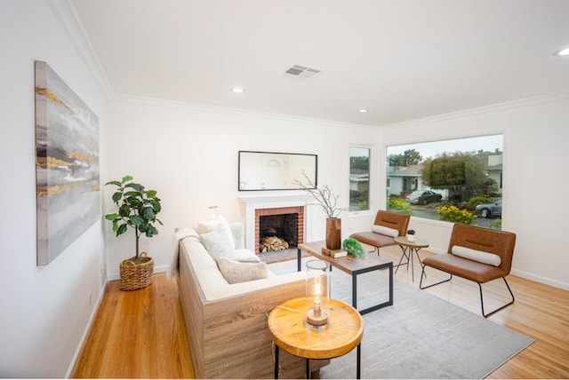 living room featuring a fireplace, ornamental molding, and light wood-type flooring