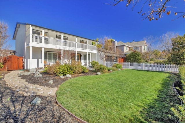 rear view of house featuring a balcony and a lawn